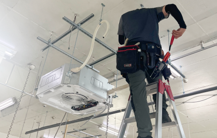 天井カセット型エアコンを新設している脚立に乗った作業員